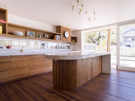 Spacious kitchen with wooden cabinetry, countertop island, and open shelving displaying decorative items.