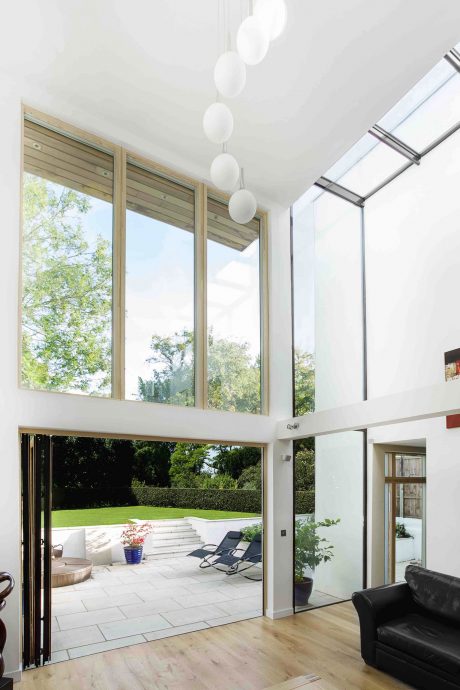 Modern open-plan interior with tall glass windows, wood accents, and pendant lighting.