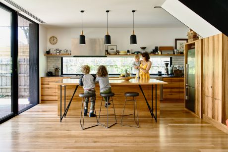 Warm, modern kitchen featuring wooden cabinetry, subway tile backsplash, and pendant lights.