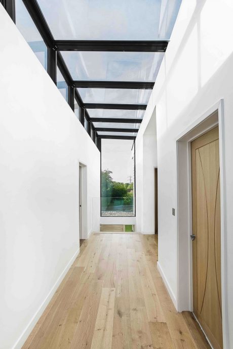 Sleek architectural design with a glass ceiling and wooden flooring, creating an open, airy space.