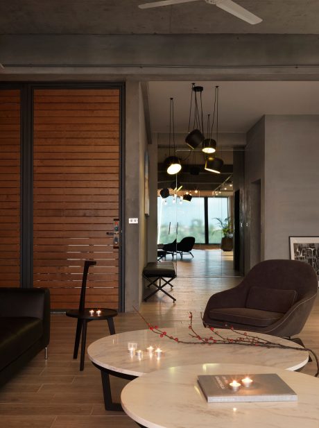 A modern living room with a sleek wooden wall, pendant lights, and a marble coffee table.