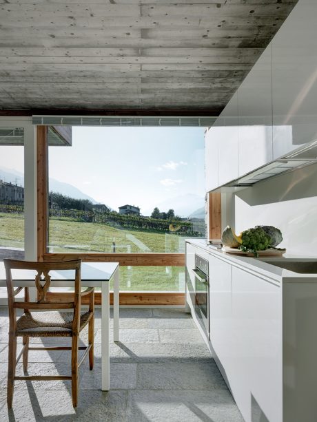 Rustic concrete ceiling, glass walls, wooden furniture, and expansive mountain views.