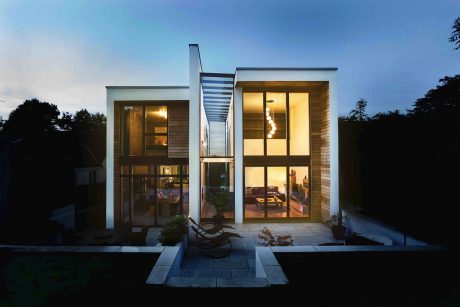 Modern two-story residence with floor-to-ceiling windows, wooden accents, and a patio.