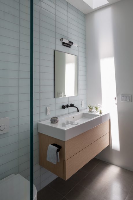 A modern, minimalist bathroom with a sleek vanity, mirror, and natural lighting.