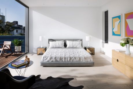 Modern, minimalist bedroom with large windows, gray bed frame, and abstract artwork on walls.