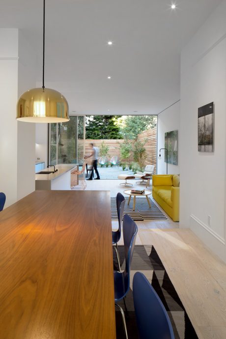 Bright modern kitchen with wooden counter and yellow accent furniture overlooking backyard.