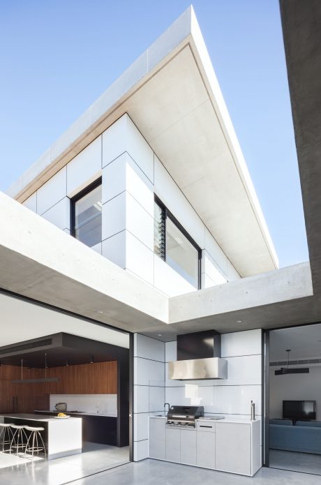 Minimalist kitchen with sleek cabinetry and dramatic angular ceiling design.