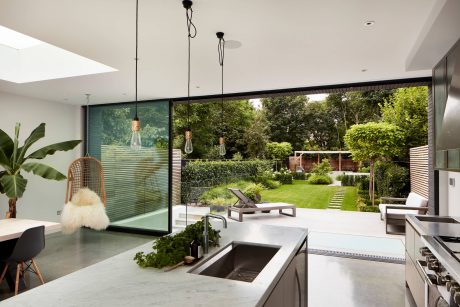 Large windows provide a panoramic view of the lush, landscaped garden. Modern kitchen fixtures and decor.