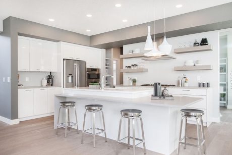 Modern, open-concept kitchen with white cabinetry, floating shelves, and stainless steel appliances.