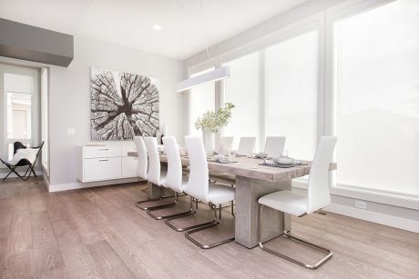 A modern dining room with a large abstract artwork, concrete table, and white chairs.