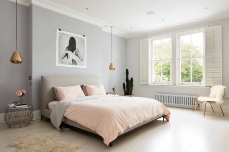 Elegant bedroom with minimalist decor, large windows, and statement lighting fixtures.