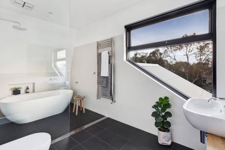 Sleek, modern bathroom with large window overlooking lush greenery and natural light.
