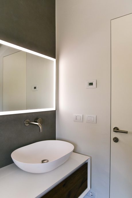 Modern bathroom vanity with a white ceramic sink, recessed mirror, and minimalist fixtures.