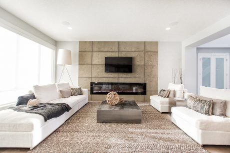 Spacious living room with a concrete panel accent wall, recessed lighting, and a large, plush sectional sofa.