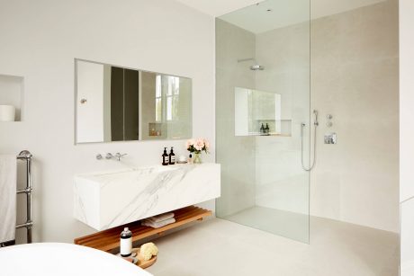 Minimalist bathroom with floating vanity, large mirror, and glass shower enclosure.