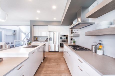 Spacious modern kitchen with sleek white cabinetry, stainless steel appliances, and wood accents.