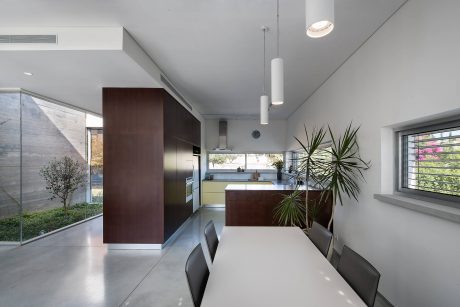 Minimalist kitchen and dining room with sleek wood and glass surfaces, modern lighting.
