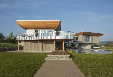 Contemporary wooden and stone residence with cantilevered balcony and minimalist exterior design.