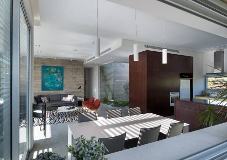 Open-concept living area with modern furnishings, concrete walls, and large windows.
