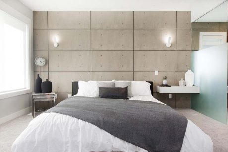 A modern, minimalist bedroom with a concrete-panel feature wall and floating nightstands.