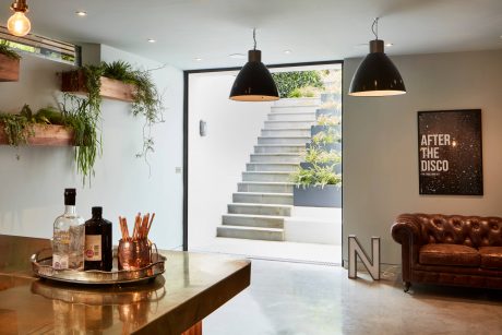Sleek, modern interior with concrete stairs, hanging plants, and metallic accents.