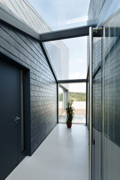 Sleek, minimalist hallway with slate grey exterior walls, large windows offering panoramic views.