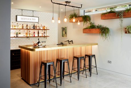 Cozy bar with clean, wooden accents, subway tiles, and hanging plants creating a warm ambiance.