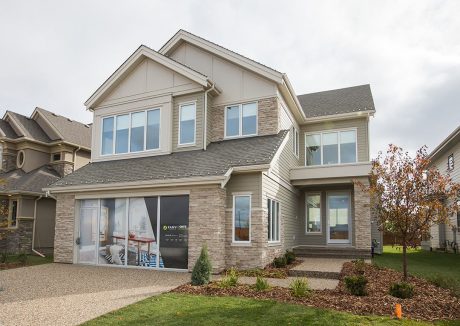 A large two-story home with a stone facade, gabled roofs, and large windows.