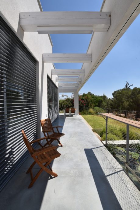Minimalist exterior architecture with wooden benches, glass walls, and landscaped yard.