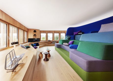 Vibrant, modern open-plan living space with wood paneling, plush seating, and colorful accents.