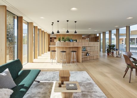 A spacious, open-concept interior with a wooden bar, pendant lighting, and plush seating.