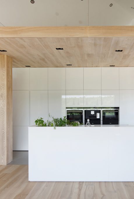 A modern, minimalist kitchen design with clean white cabinetry and warm wood accents.