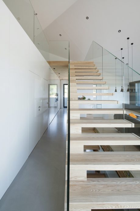 A modern, minimalist staircase with floating wooden steps and glass balustrades.