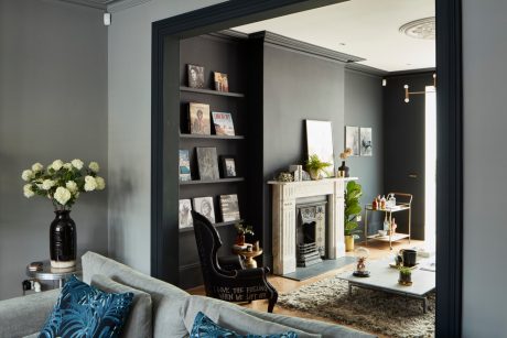 Elegantly styled living room with ornate fireplace, shelves, and cozy decor.