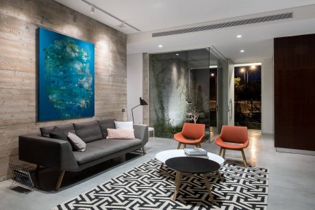 Sleek, modern living space with concrete walls, abstract artworks, and playful furniture.