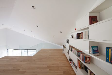 An airy, modern interior with a wood-paneled floor, built-in shelves, and natural light.