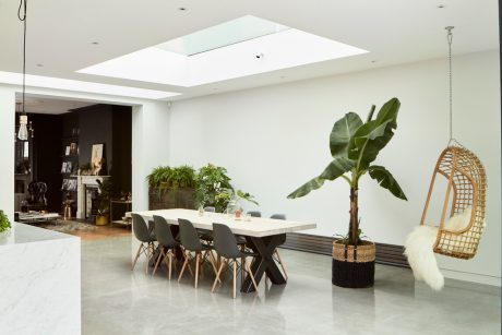 Bright, minimalist dining room with large skylight, potted plants, and modern furniture.