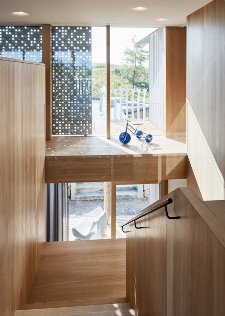 Modern and airy interior with wooden accents, patterned glass panels, and a blue tricycle.