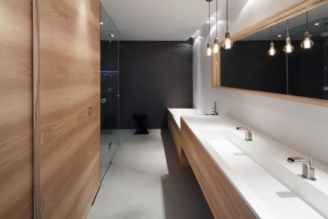 Modern bathroom with wooden vanity, pendant lighting, and seamless glass shower.