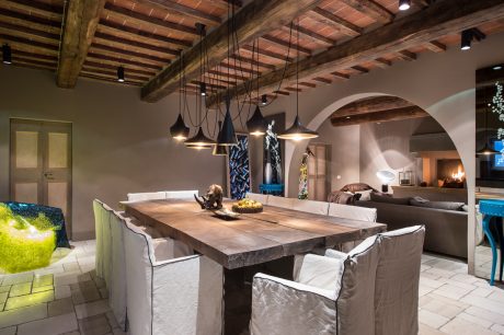 A rustic, open-concept living space with a large wooden dining table and pendant lights.