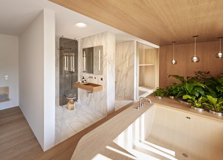 Sleek, modern bathroom with marble accents, wooden vanity, and lush greenery.