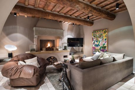 Rustic beamed ceiling, fireplace, comfortable sofas, and vibrant artwork in cozy living room.