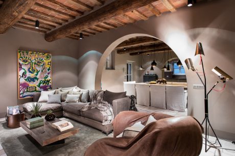 Rustic beams, arched doorway, eclectic decor, and cozy living space with modern touches.
