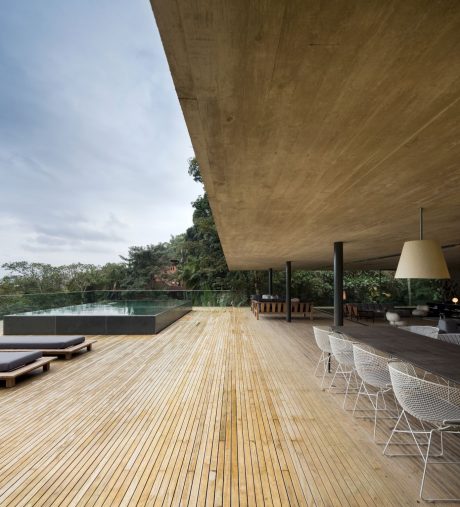 Expansive outdoor deck with wooden floors, covered seating area, and infinity pool.