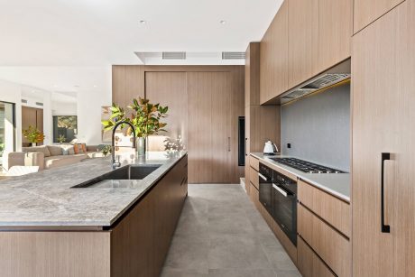 Modern kitchen with sleek wood cabinetry, grey countertops, and integrated appliances.