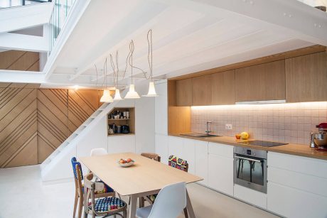 A modern, open-plan kitchen with clean white cabinets, wood accents, and stylish lighting.
