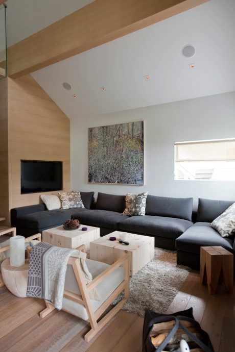 Cozy living room with sleek sectional, wooden accents, and a nature-inspired wall art.
