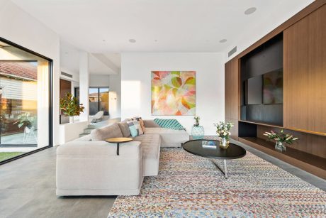 Spacious modern living room with plush sectional, colorful artwork, and wooden TV cabinet.