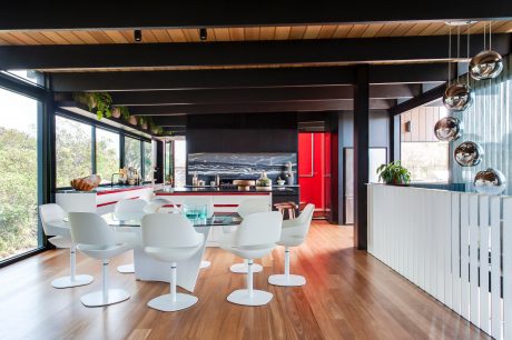 A modern and open kitchen-dining space with sleek wooden beams, glass walls, and stylish furnishings.