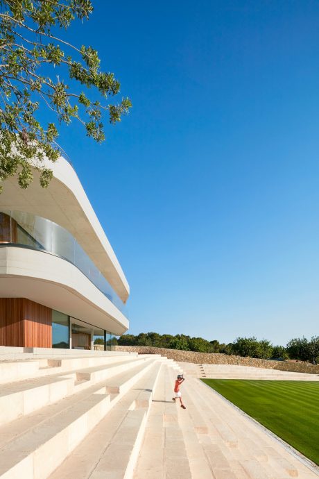 Striking curved façade with surrounding gardens and a grassy lawn area.